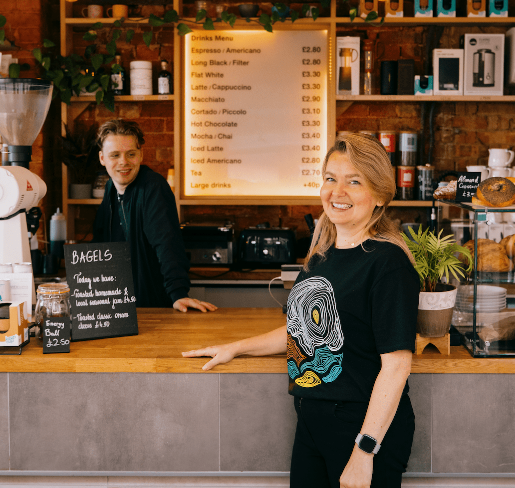 Two baristas smiling at the counter of the Missing bean Cafe in Banbury, Oxford.